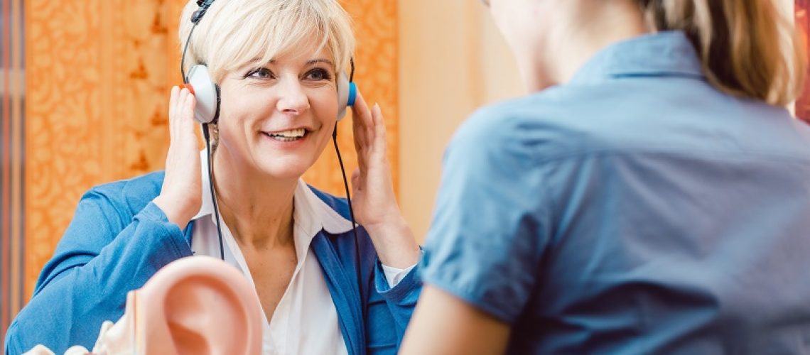 Older woman or female pensioner with a hearing problem takes test